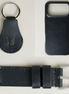 Three premium leather items for apple products in midnight black: airtag keychain with metal key ring and embossed Markore logo, iphone 17 case with embossed Markore logo and watch strap with silver stainless steel buckle and adapter.