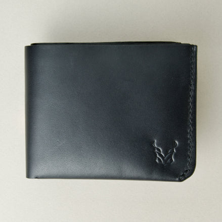 Outside view of midnight black full-grain leather wallet featuring a seamless bottom edge, handmade stitching and embossed logo. Markore Assam Silk.