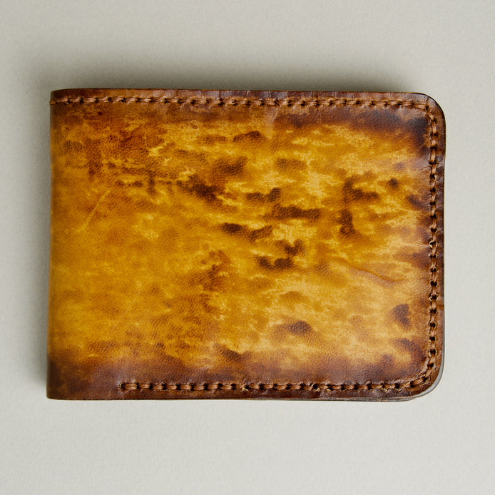 Front view of hand-painted full-grain leather bifold wallet in amber and brown, featuring handmade stitching. Markore Canvas Flame.