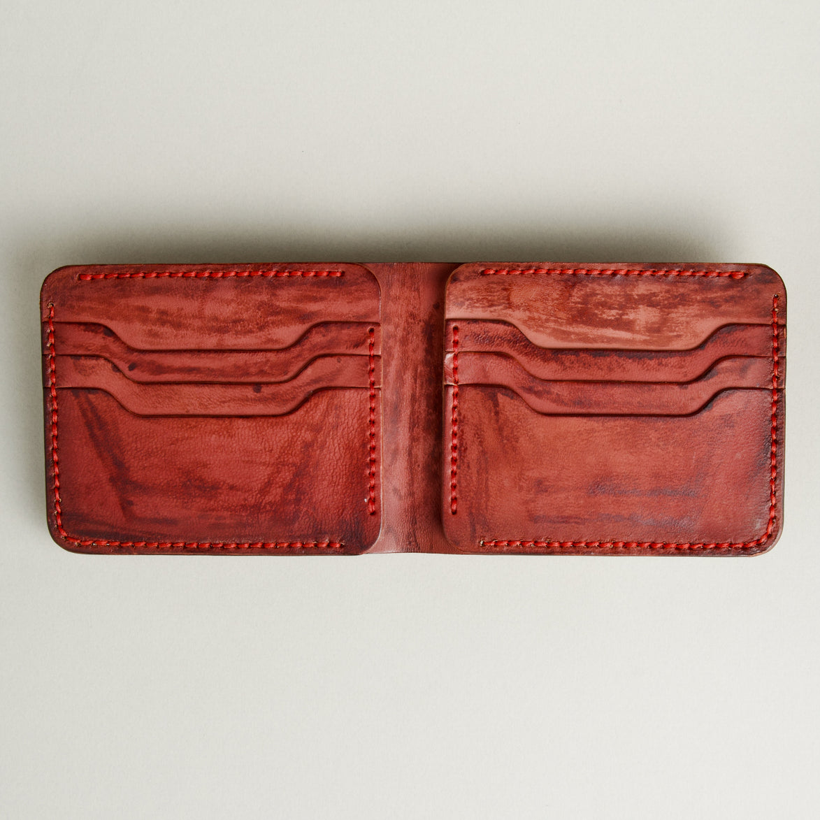 Inside view of hand-painted full-grain leather bifold wallet in red, featuring card slots and handmade stitching. Markore Canvas Flame.