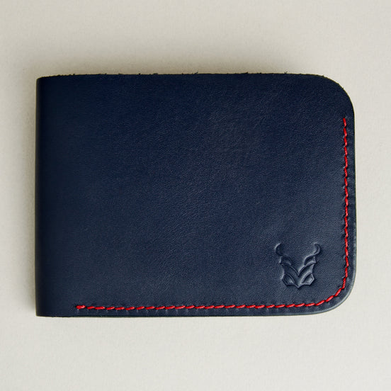 Front view of full-grain leather bifold wallet with hand-stitched red thread in Dark Blue and embossed logo. Markore Hunza Arc.