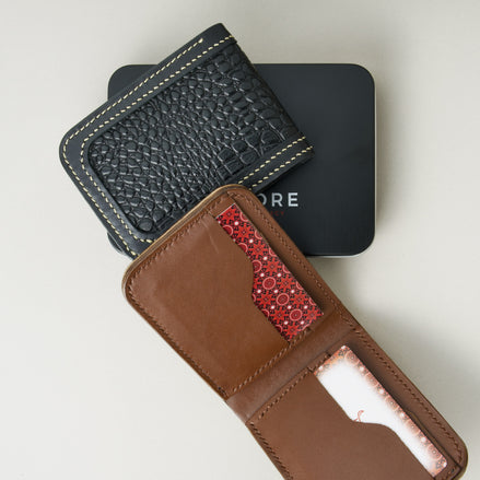 Front view of obsidian black croc-embossed full-grain leather bifold wallet and interior view of espresso brown wallet placed on a black Markore branded box.
