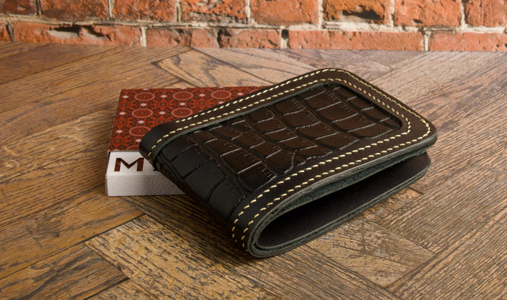 markore indus sultan black leather wallet on a wooden surface with a brick wall background