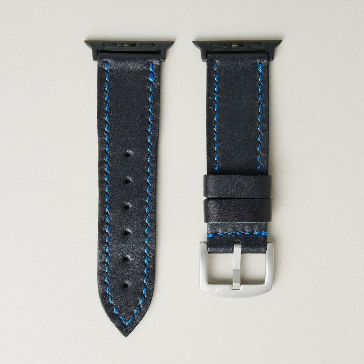 Midnight Black full-grain leather watch strap with black stainless steel adapters and silver buckle, featuring blue handmade stitching and matching blue loops. Markore Hour Line.