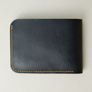 Back view of full grain leather bifold wallet in midnight black, featuring handmade stitching in amber. Markore Hunza Fold.
