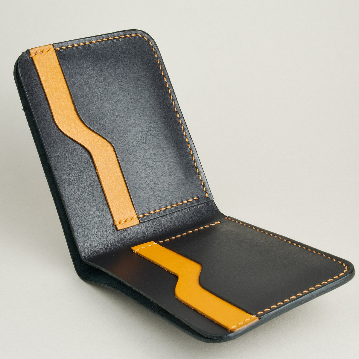 Inside view of full grain leather bifold wallet in midnight black, featuring handmade stitching and card slots in amber. Markore Hunza Fold.