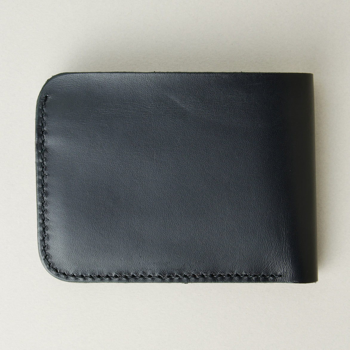 Back view of full grain leather bifold wallet in midnight black featuring handmade stitching. Markore Hunza Fold.