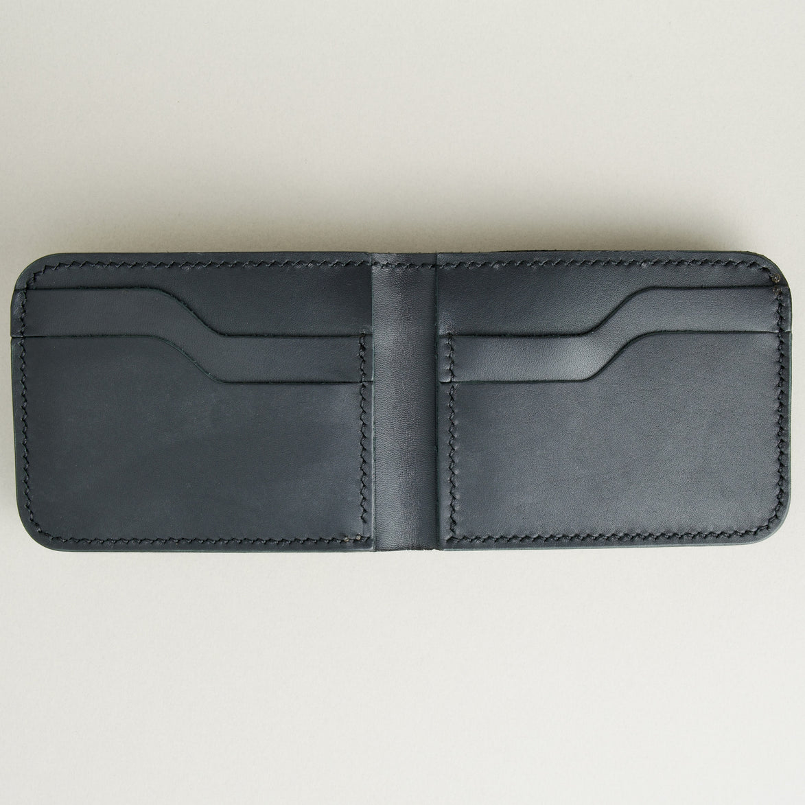 Inside view of full grain leather bifold wallet in midnight black featuring handmade stitching and card slots. Markore Hunza Fold.