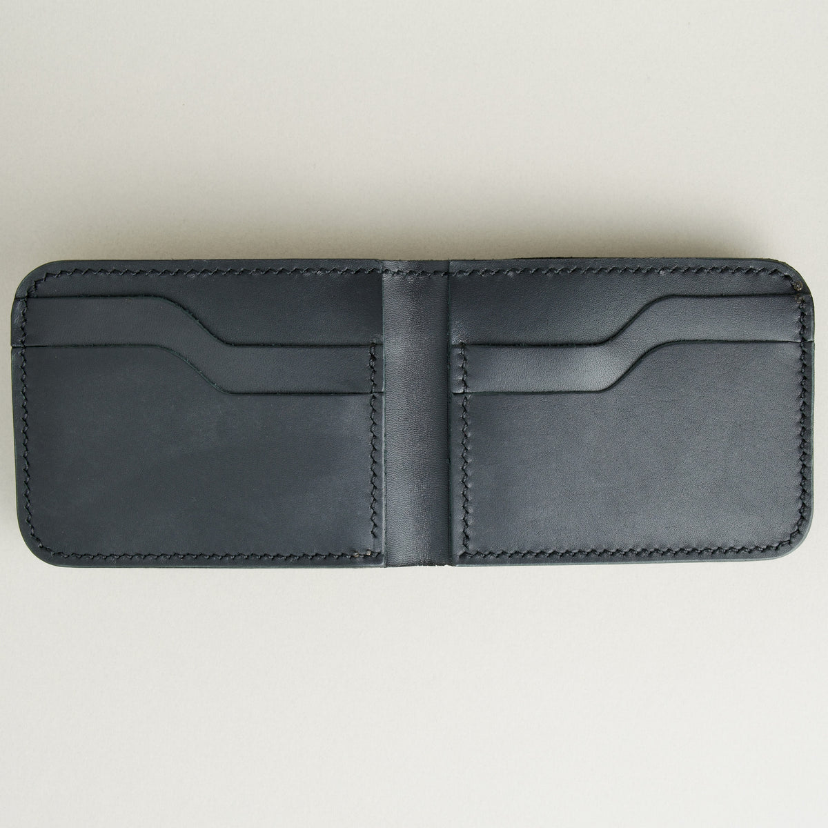 Inside view of full grain leather bifold wallet in midnight black featuring handmade stitching and card slots. Markore Hunza Fold.