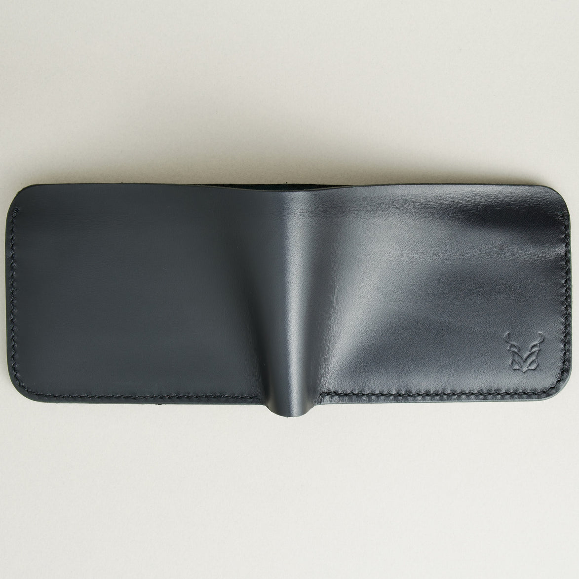 Outside view of full grain leather bifold wallet in midnight black, featuring handmade stitching and embossed logo. Markore Hunza Fold.