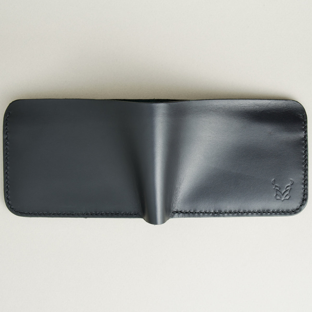 Outside view of full grain leather bifold wallet in midnight black, featuring handmade stitching and embossed logo. Markore Hunza Fold.