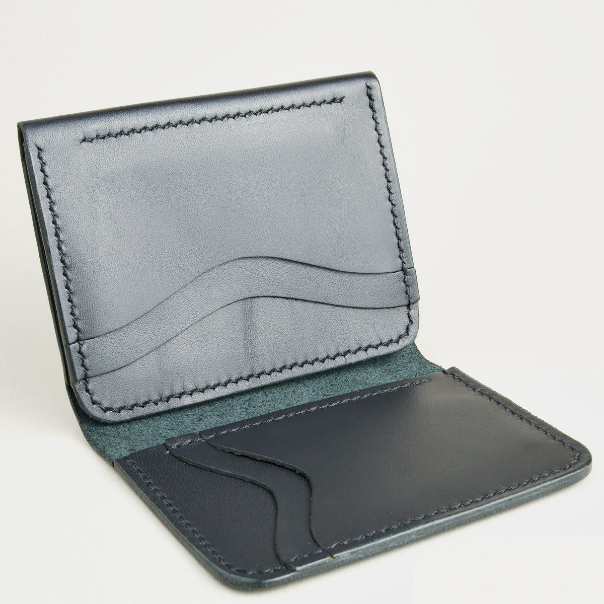 Side view of midnight black full-grain leather flap fold wallet featuring a flap closure, vertical and horizontal card slots and handmade stitching. Markore Khaas Andaz.