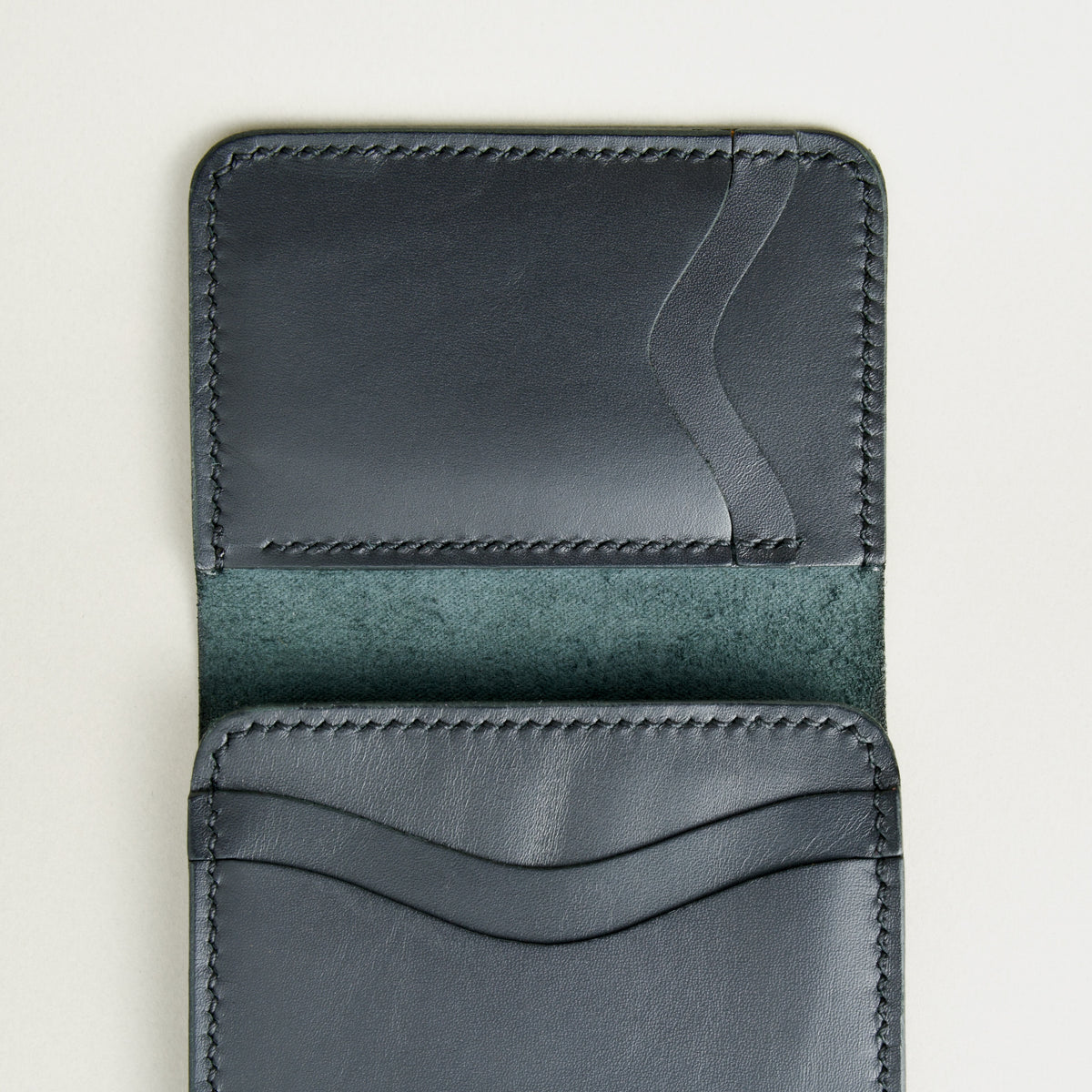 Inside view of midnight black full-grain leather flap fold wallet featuring horizontal and vertical card slots and handmade stitching. Markore Khaas Andaz.
