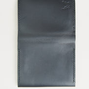 Outside view of midnight black full-grain leather flap fold wallet featuring handmade stitching and embossed logo. Markore Khaas Andaz.