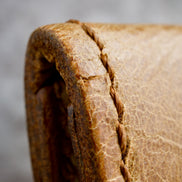 Close-up of a textured brown leather surface with handmade stitching