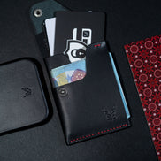 markore niva heritage in midnight black with red stitching and markore shell frame iphone 17 pro leather case sitting on a black surface