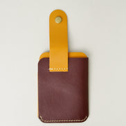 Back view of full grain leather card holder in espresso brown and amber, featuring an open leather loop with brass press button and handmade stitching. Markore Niva Loop.