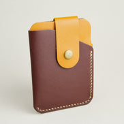 Side view of full grain leather card holder in espresso brown and amber, featuring a leather loop with brass press button and handmade stitching. Markore Niva Loop.