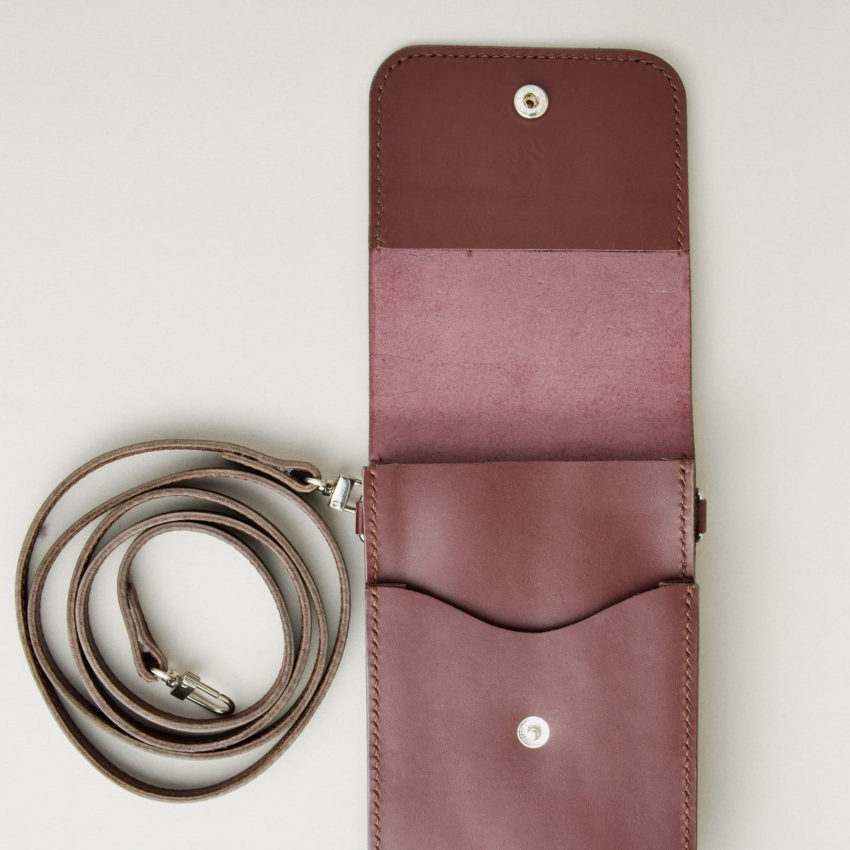 Inside view of vertical full-grain leather crossbody bag and matching shoulder strap in Espresso Brown, showing handmade stitching and stainless steel press stud. Markore Nora Veldt.