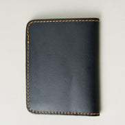 Back view of midnight black full-grain leather wallet featuring amber handmade stitching. Markore Ravi Fold.