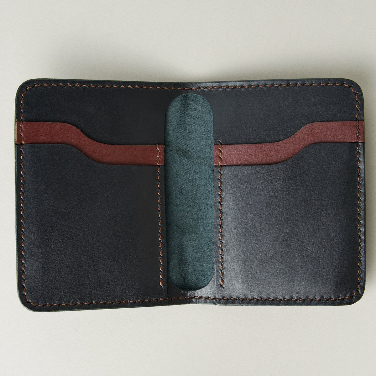 Inside view of midnight black full-grain leather wallet featuring midnight black and espresso brown card slots and espresso brown handmade stitching. Markore Ravi Fold.