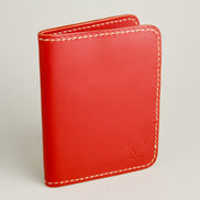 Side view of red full-grain leather wallet featuring ivory handmade stitching and embossed logo. Markore Ravi Fold.