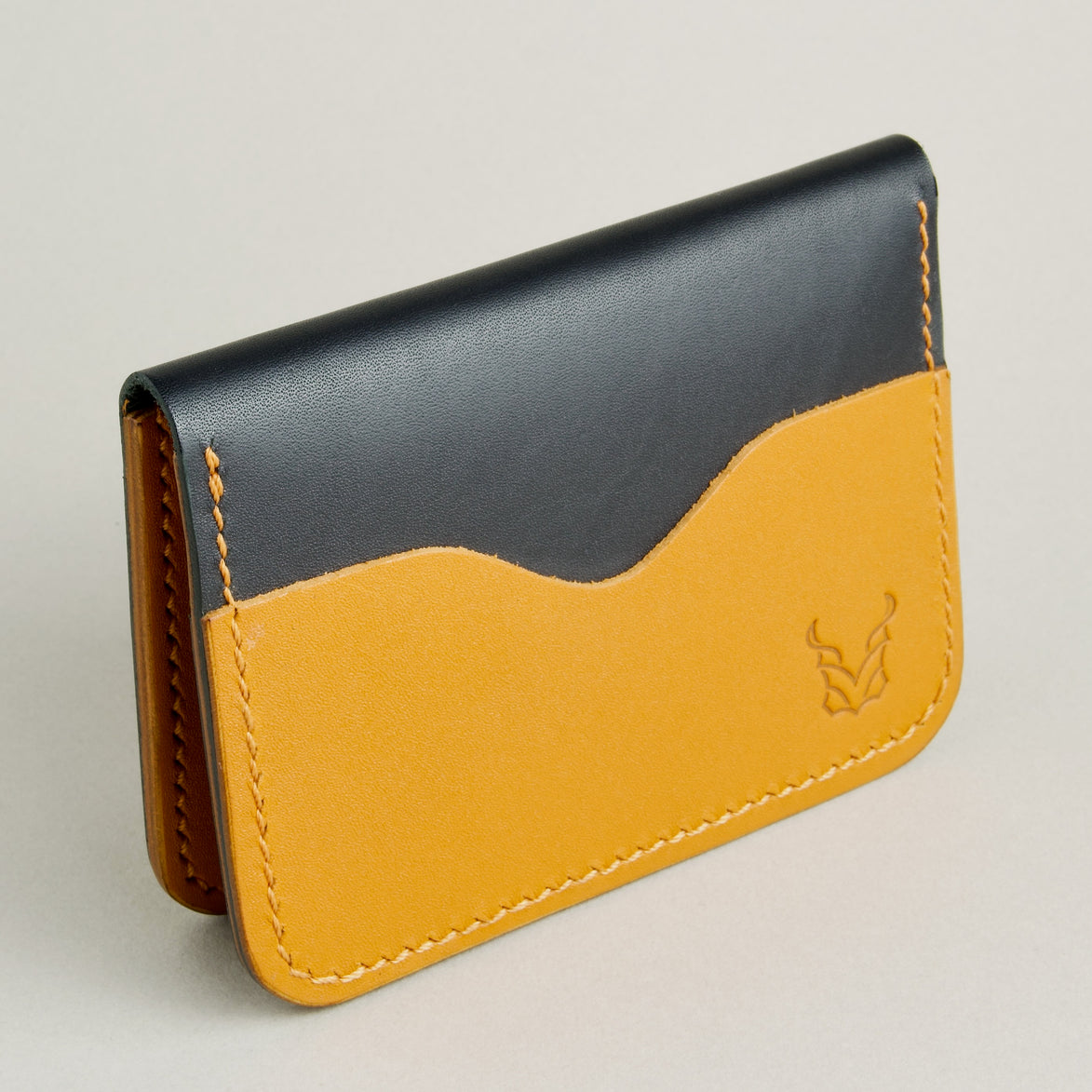 Side view of midnight black full-grain leather wallet featuring amber card slot, amber handmade stitching and embossed logo. Markore Ravi Slip.