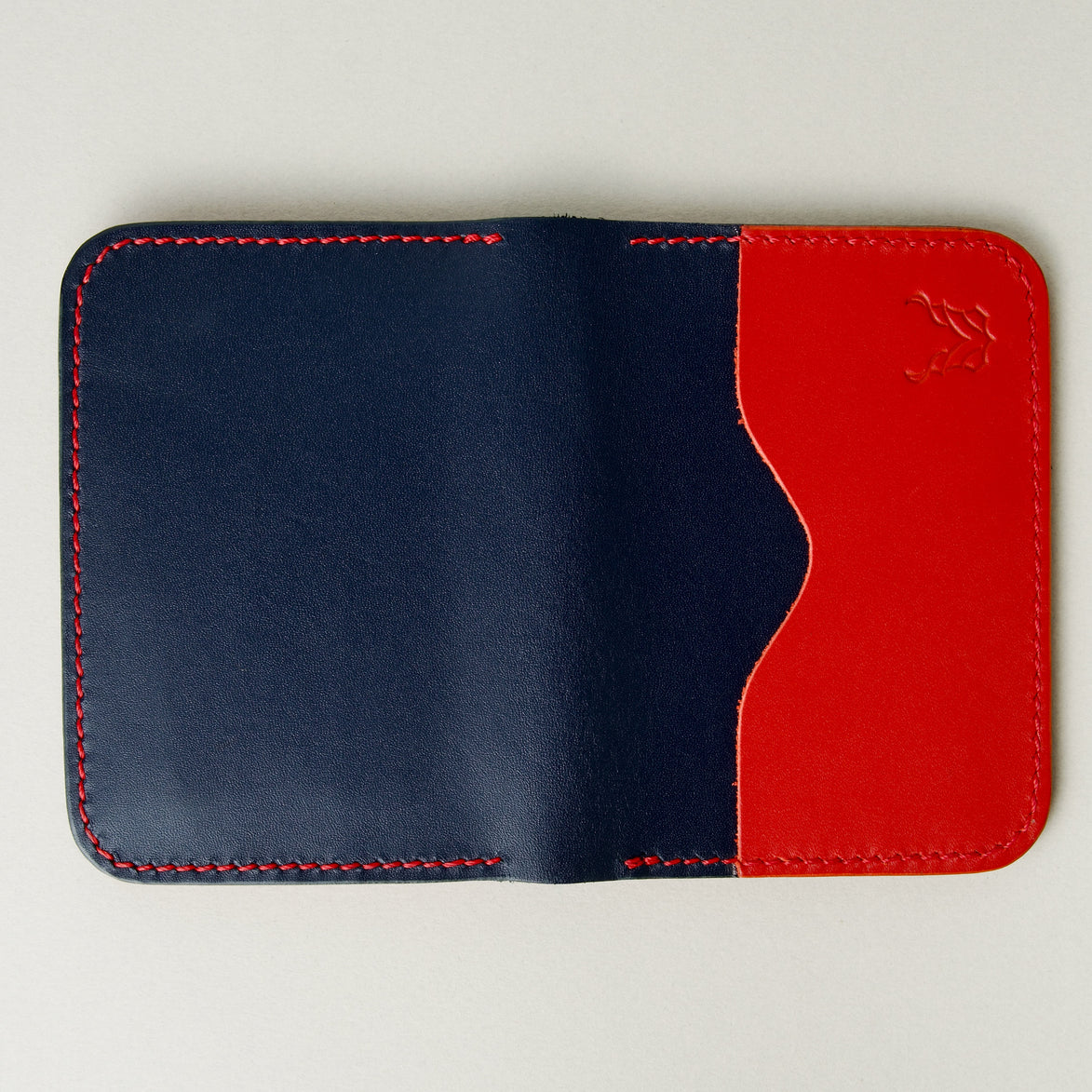 Outside view of dark blue full-grain leather wallet featuring red card slot, red handmade stitching and embossed logo. Markore Ravi Slip.