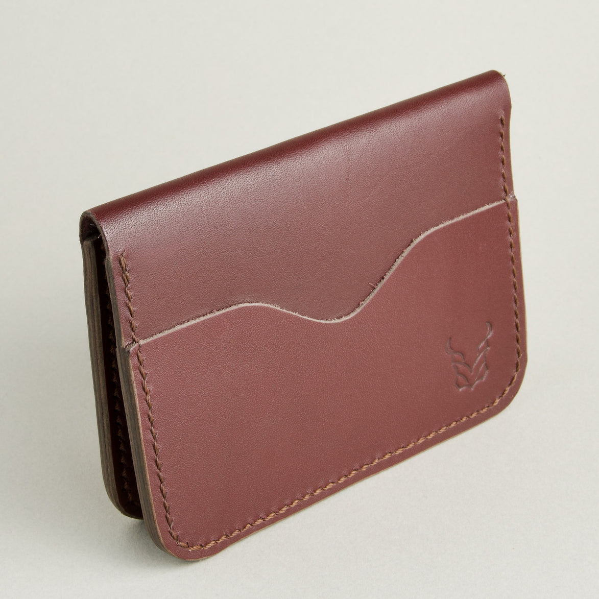 Side view of espresso brown full-grain leather wallet featuring card slot, handmade stitching and embossed logo. Markore Ravi Slip.