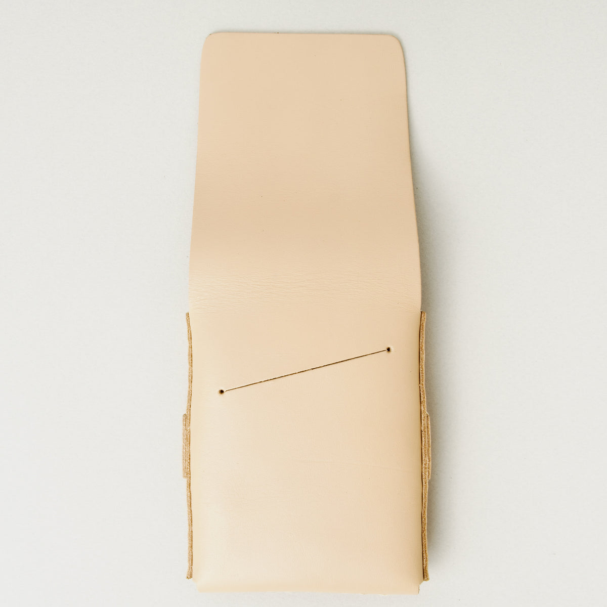Back view of natural full-grain leather flap wallet with open flap featuring a card slot and handmade stitching. Markore Sutlej Vault.