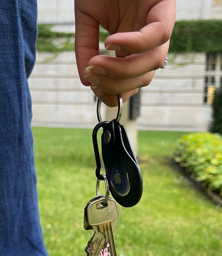 Hand holding keys with a blurred background of grass and a building