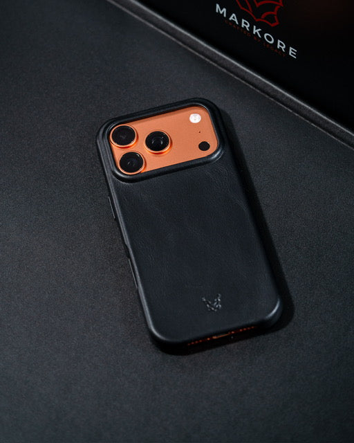 Lifestyle picture of leather iphone 17 pro phone case with embossed logo on an orange iphone on a black background