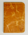 Front view of vertical full-grain leather passport holder in amber, featuring handmade stitching and embossed logo. Markore Voyage Pass.